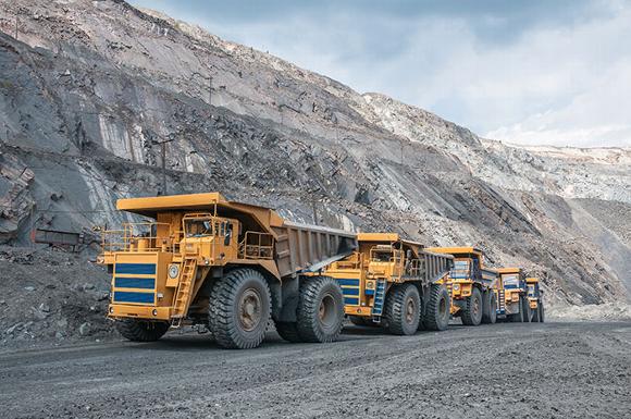 mining trucks driving gravel road in quarry
